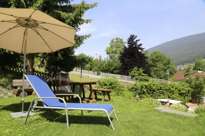 a blue chair and an umbrella in the grass at Garni Panoramik in Ortisei
