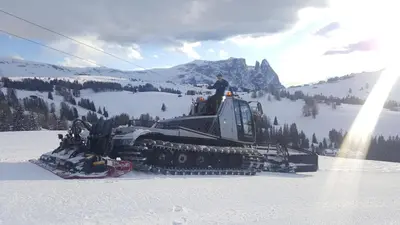 a man is standing on top of a snow bulldozer in the snow at Garni Panoramik in Ortisei