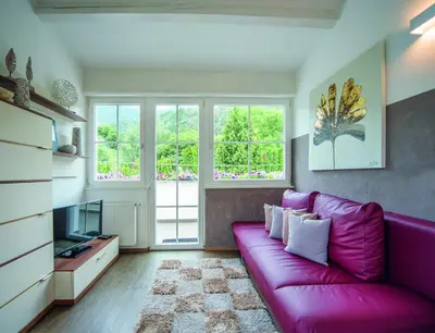a living room with a purple couch and a tv at Gartenhof in Bressanone