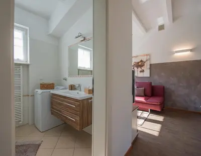 a bathroom with a sink and a red couch at Gartenhof in Bressanone
