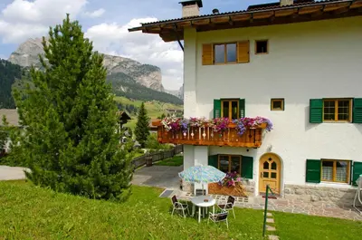 a house with a balcony with flowers on it at Villa Insam Apartment in Selva di Val Gardena