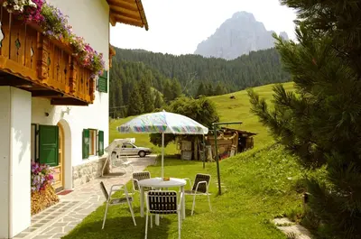 a table and chairs with an umbrella in a yard at Villa Insam Apartment in Selva di Val Gardena