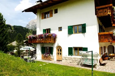 a white house with a balcony with flowers on it at Villa Insam Apartment in Selva di Val Gardena