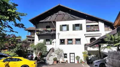 a yellow car parked in front of a white building at Garni Meinrad in Ora/Auer
