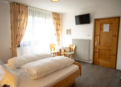 a bedroom with a bed and a window and a table at Garni Meinrad in Ora/Auer