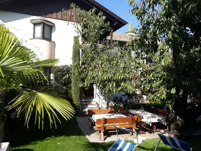 a garden with a bench and chairs in front of a house at Garni Meinrad in Ora/Auer
