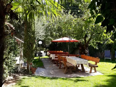 a group of tables and benches with an umbrella at Garni Meinrad in Ora/Auer