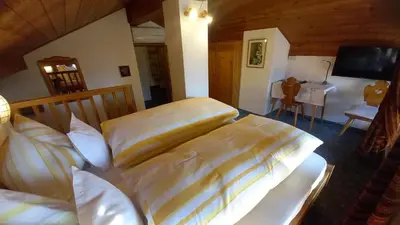 a bedroom with two beds and a table and a television at Garni Meinrad in Ora/Auer