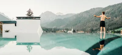 a man standing on top of a body of water at Al Plan, A mountain moving hotel in San Vigilio Di Marebbe