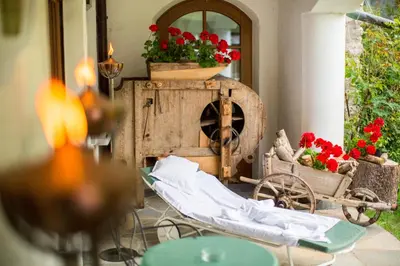 a patio with a table and flowers and a mirror at Al Plan, A mountain moving hotel in San Vigilio Di Marebbe