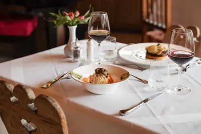 a table with a bowl of food and glasses of wine at Al Plan, A mountain moving hotel in San Vigilio Di Marebbe