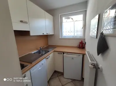 a small kitchen with white cabinets and a sink at Residence Montebel in Tesero