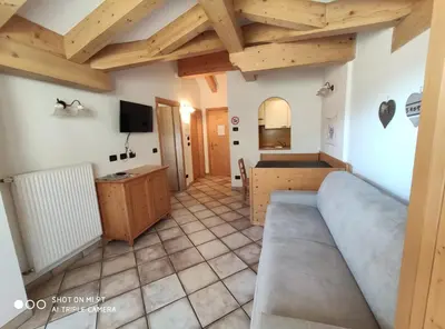 a living room with a couch in a room with wooden ceilings at Residence Montebel in Tesero