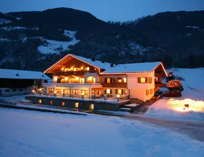 a large house in the snow at night at Hotel Foestlerhof in Villa Ottone