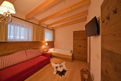 a living room with a red couch and a tv at Hotel Foestlerhof in Villa Ottone