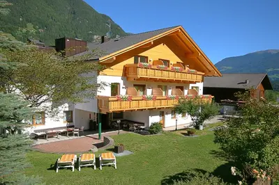 a house with a deck and chairs on the yard at Hotel Foestlerhof in Villa Ottone