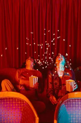 two people sitting on a couch in a theater with popcorn at Amadeus Ora & Amore in Caldaro