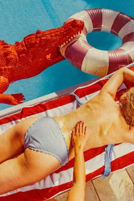 a woman laying on a towel next to a swimming pool at Amadeus Ora & Amore in Caldaro