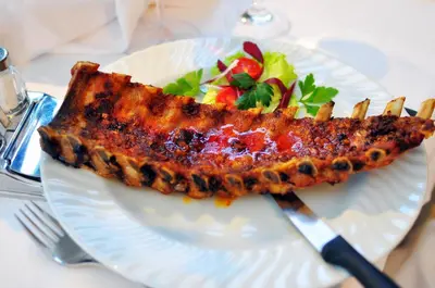 a white plate with a piece of meat and salad at Bad St Isidor in Bolzano