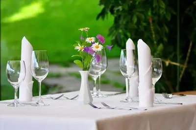 a table with wine glasses and flowers in a vase at Bad St Isidor in Bolzano