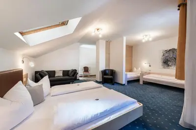 a hotel room with two beds and a couch at Hotel Wiedenhofer in Terento