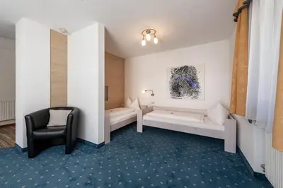 a room with two beds and a chair at Hotel Wiedenhofer in Terento