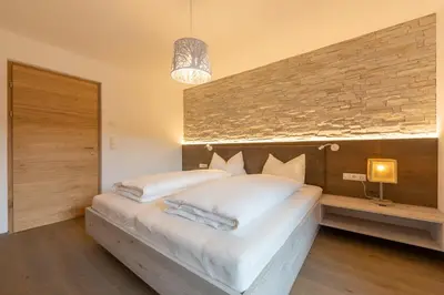 a bedroom with a large white bed with a stone wall at Ditterhof in Tesido