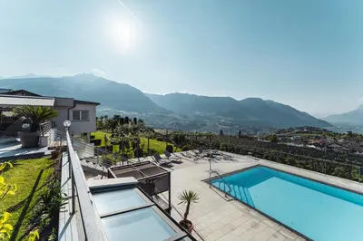 a view of a house with a swimming pool and mountains at Appartement-Hotel Beatenhof in Tirolo
