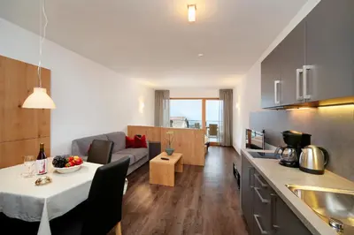 a kitchen and living room with a table and a couch at Appartement-Hotel Beatenhof in Tirolo