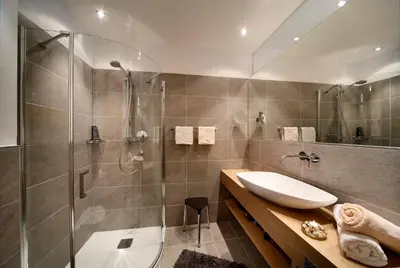 a bathroom with a shower and a sink and a tub at Appartement-Hotel Beatenhof in Tirolo