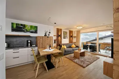 a kitchen and living room with a table and chairs at Appartement-Hotel Beatenhof in Tirolo