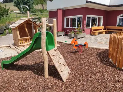 a playground with a slide in a yard at Hotel Amaten in Brunico