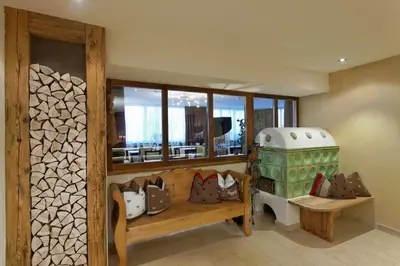 a room with a bench and a stove and windows at Hotel Amaten in Brunico