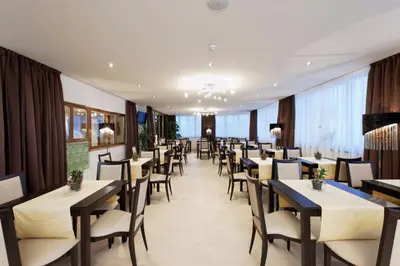 a restaurant with rows of tables and chairs at Hotel Amaten in Brunico