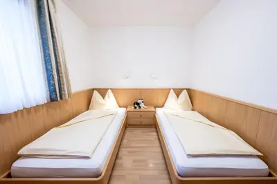 two twin beds in a room with a window at Ciasa Mascotte in San Vigilio Di Marebbe