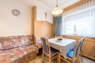 a dining room with a table and a couch at Ciasa Mascotte in San Vigilio Di Marebbe