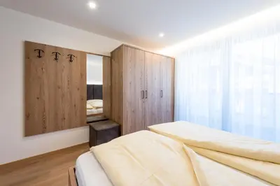 a bedroom with two beds and a large window at Ciasa Mascotte in San Vigilio Di Marebbe