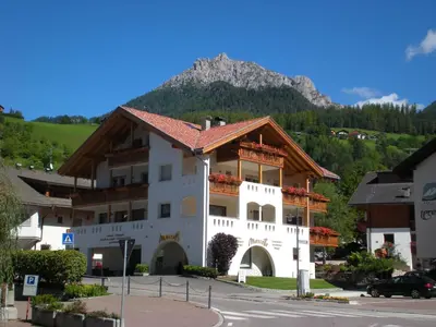 a large building with a mountain in the background at Ciasa Mascotte in San Vigilio Di Marebbe