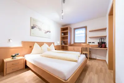 a bedroom with a bed and a desk in it at Ciasa Mascotte in San Vigilio Di Marebbe