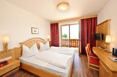 a bedroom with a bed and a desk and a computer at Hotel St. Justina Hof in Appiano sulla Strada del Vino