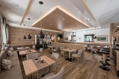 a restaurant with wooden floors and tables and chairs at Hotel St. Justina Hof in Appiano sulla Strada del Vino