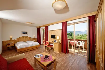 a hotel room with a bed and a desk with a table at Hotel St. Justina Hof in Appiano sulla Strada del Vino