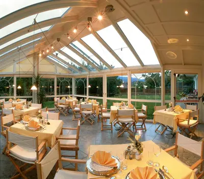 a restaurant with tables and chairs in a conservatory at Hotel St. Justina Hof in Appiano sulla Strada del Vino