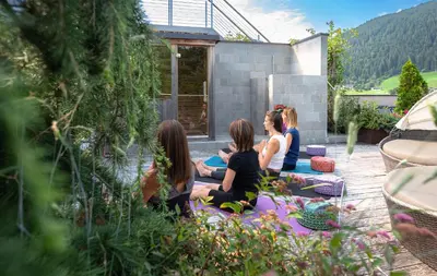 a group of women sitting on a blanket in a garden at Bio & BikeHotel Steineggerhof in Collepietra