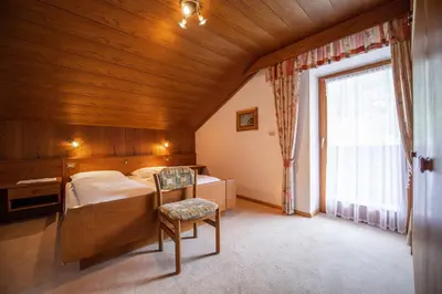 a bedroom with a bed and a chair and a window at Apartments Zilli in Laion