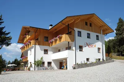 a large white building with a wooden roof at Jausenstation Moar in Funes