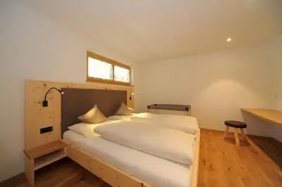 a bedroom with a bed with a wooden headboard and a window at Jausenstation Moar in Funes