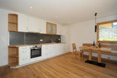 a kitchen with white cabinets and a wooden table with a wooden table at Jausenstation Moar in Funes