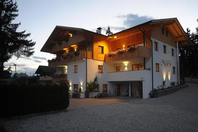a large white building with a sunset in the background at Jausenstation Moar in Funes