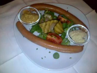 a plate of food with a hot dog and vegetables at Hotel Gasthof WASTL in Appiano sulla Strada del Vino
